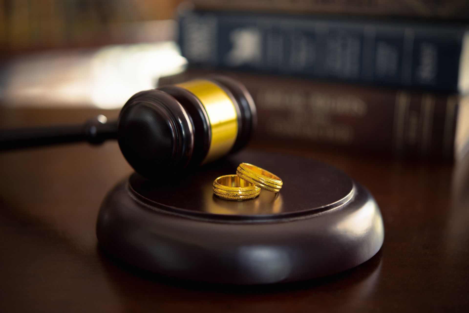 A pair of wedding rings are sitting on top of a wooden gavel.