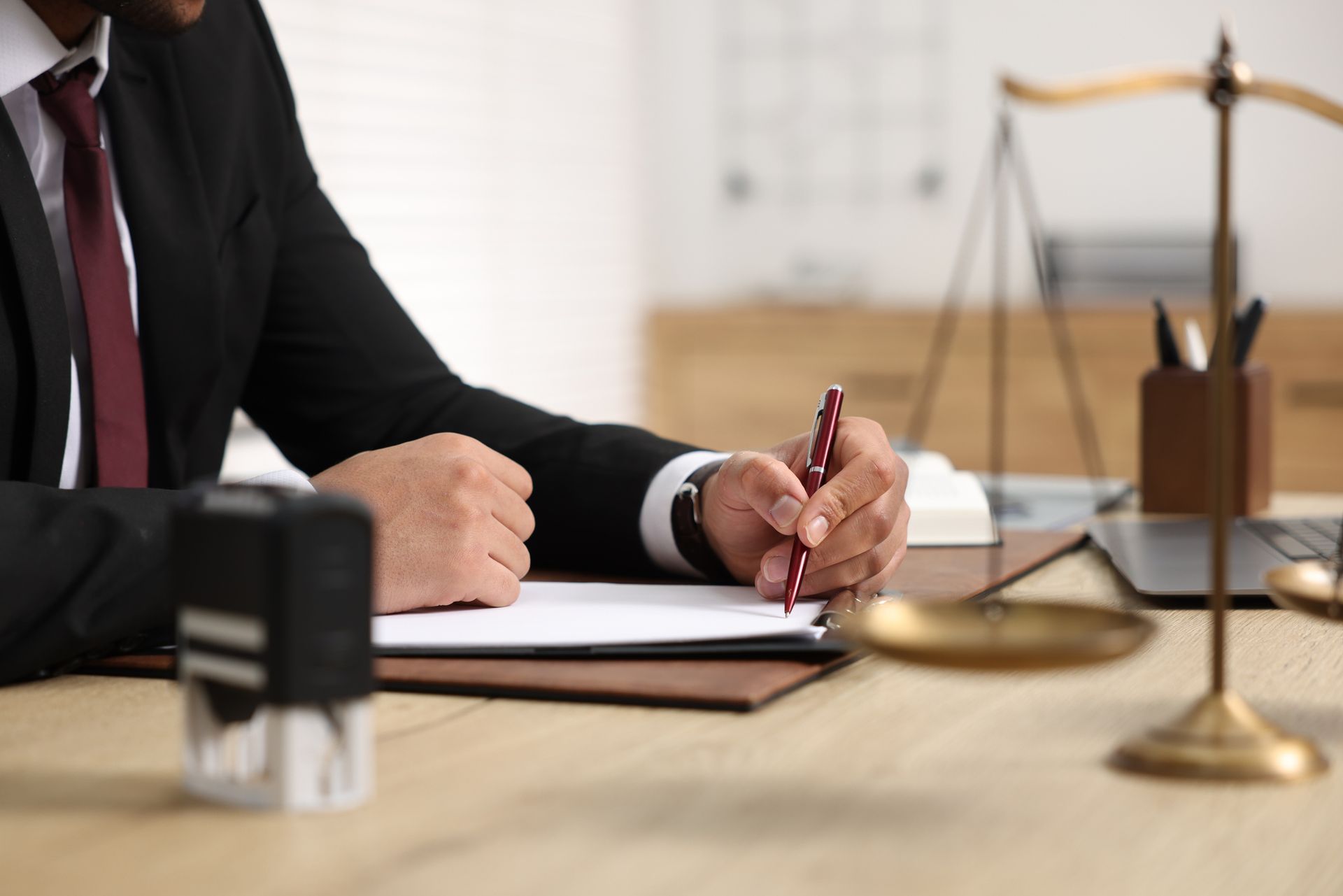 A man in a suit and tie is sitting at a desk writing on a piece of paper.