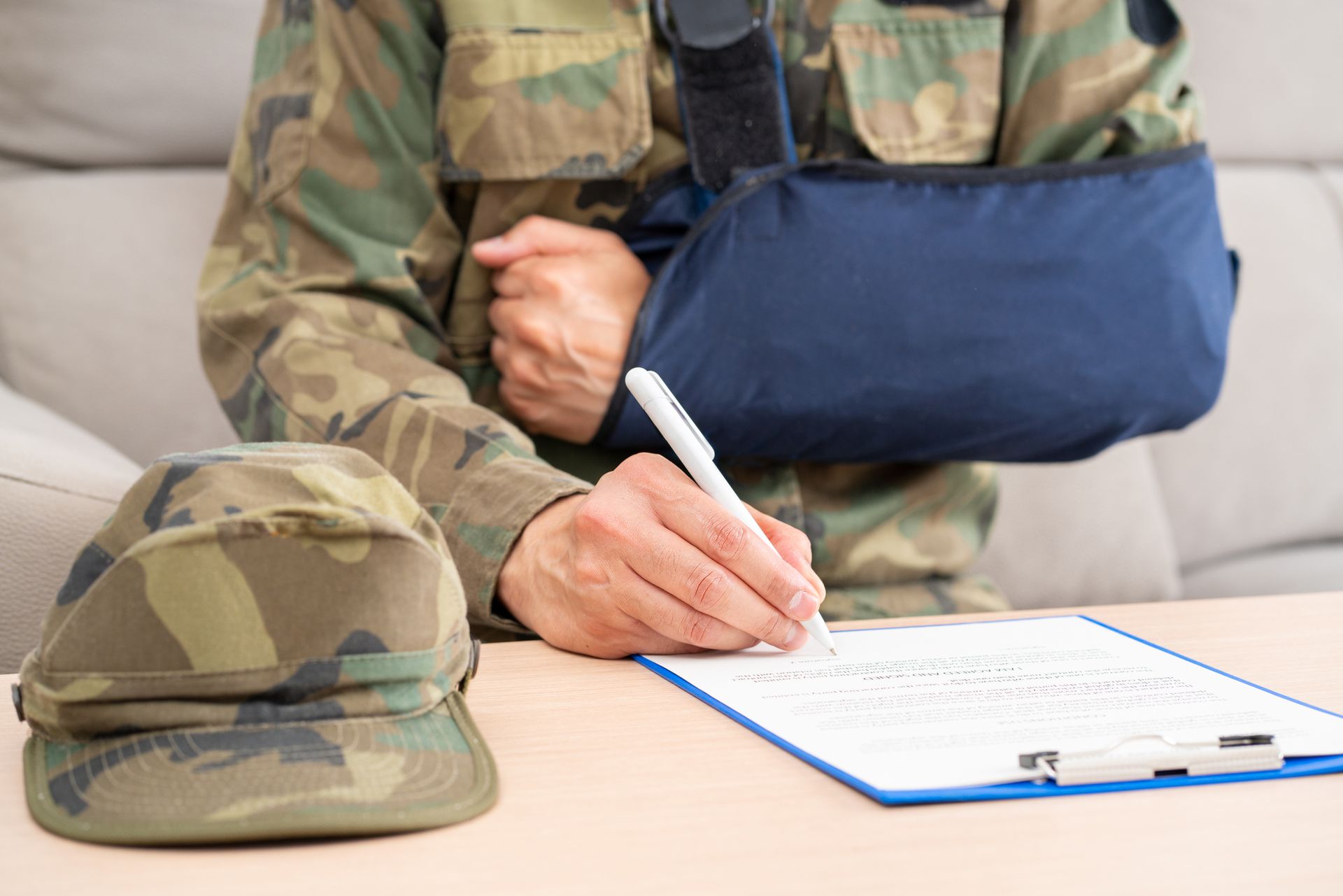 A soldier with a broken arm is writing on a clipboard.