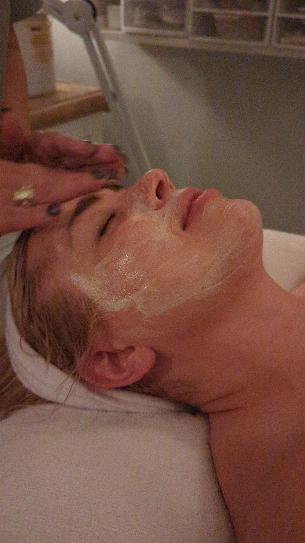 A woman 's face is visible through a hole in a pink wall.