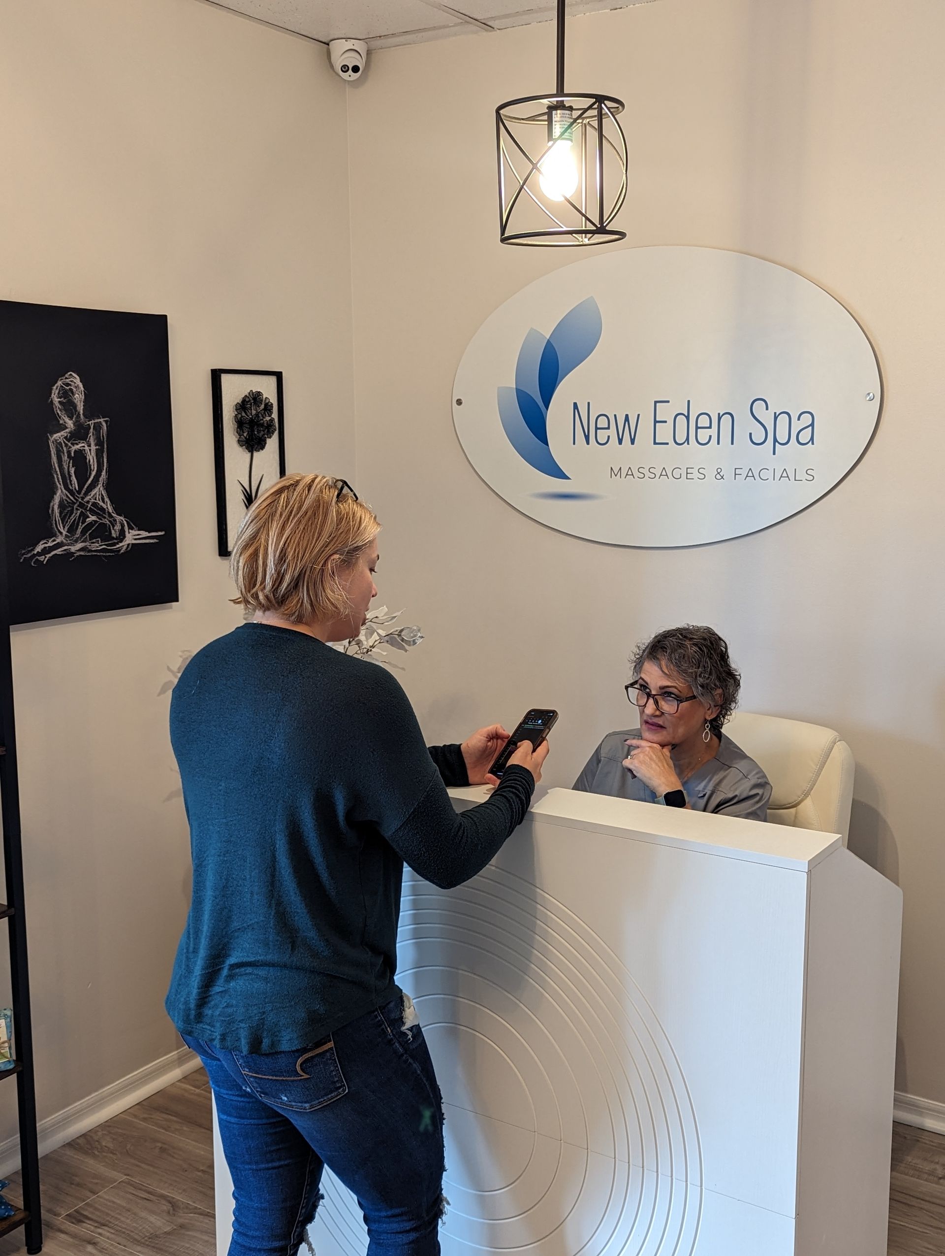 A woman is standing in front of a reception desk in New Eden Spa.