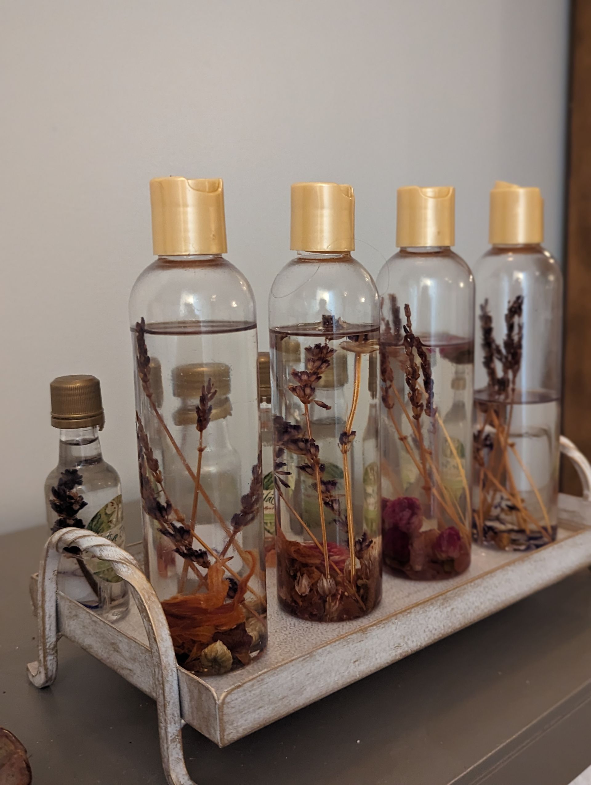 A tray with bottles filled with liquid and flowers on it.