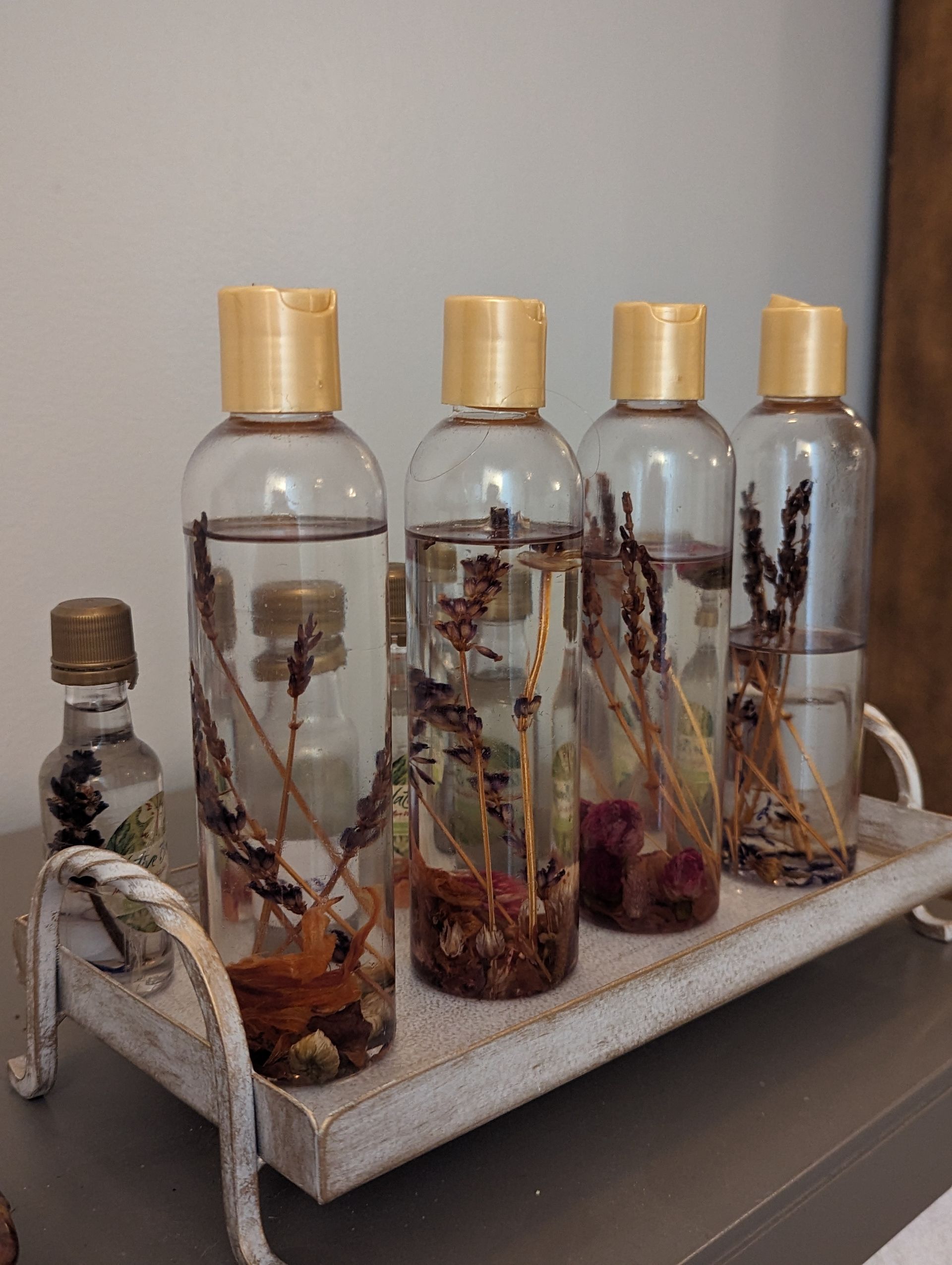 A tray of bottles filled with liquid and flowers on a table.