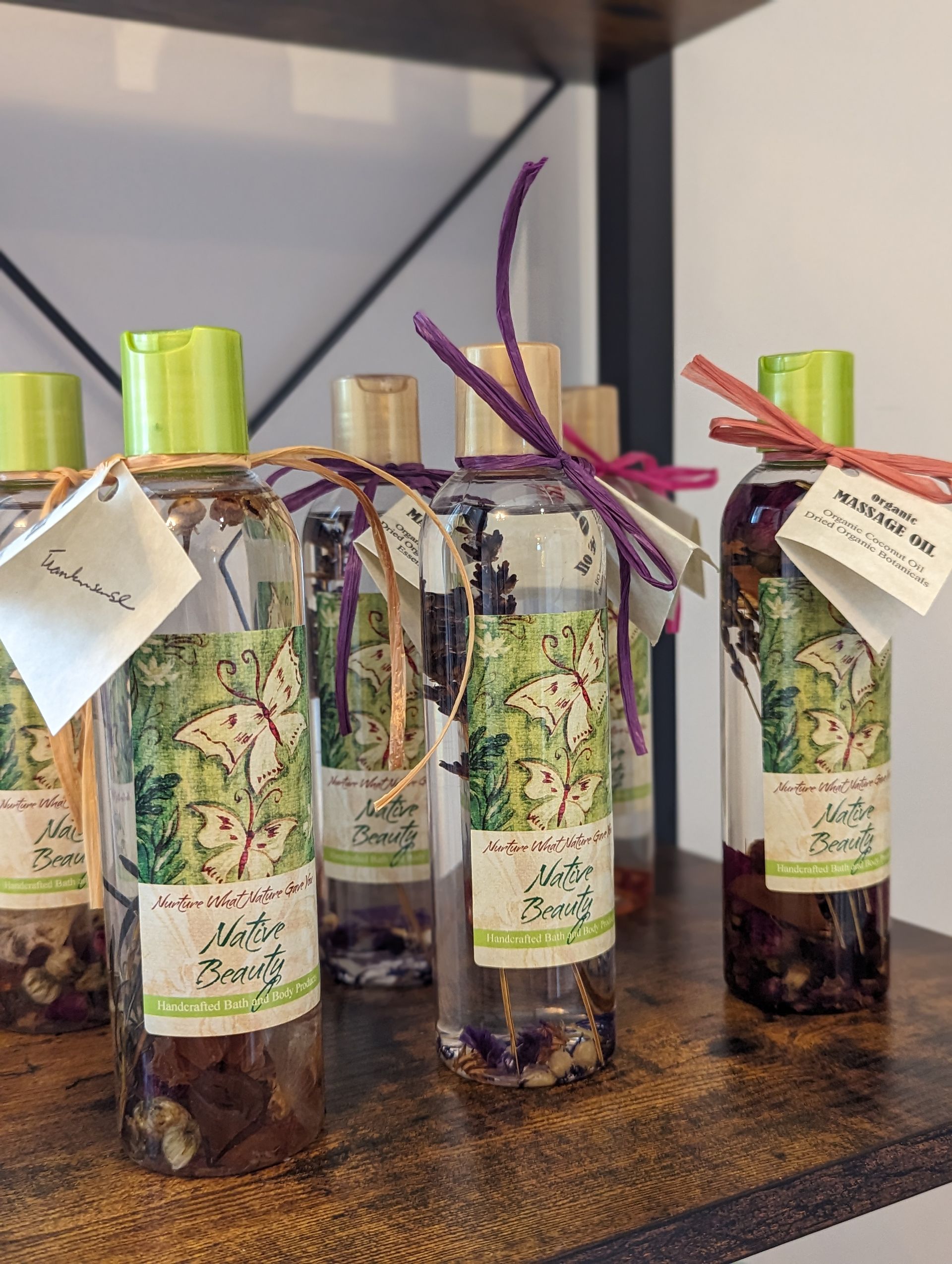 A bunch of bottles of perfume are sitting on a wooden shelf.