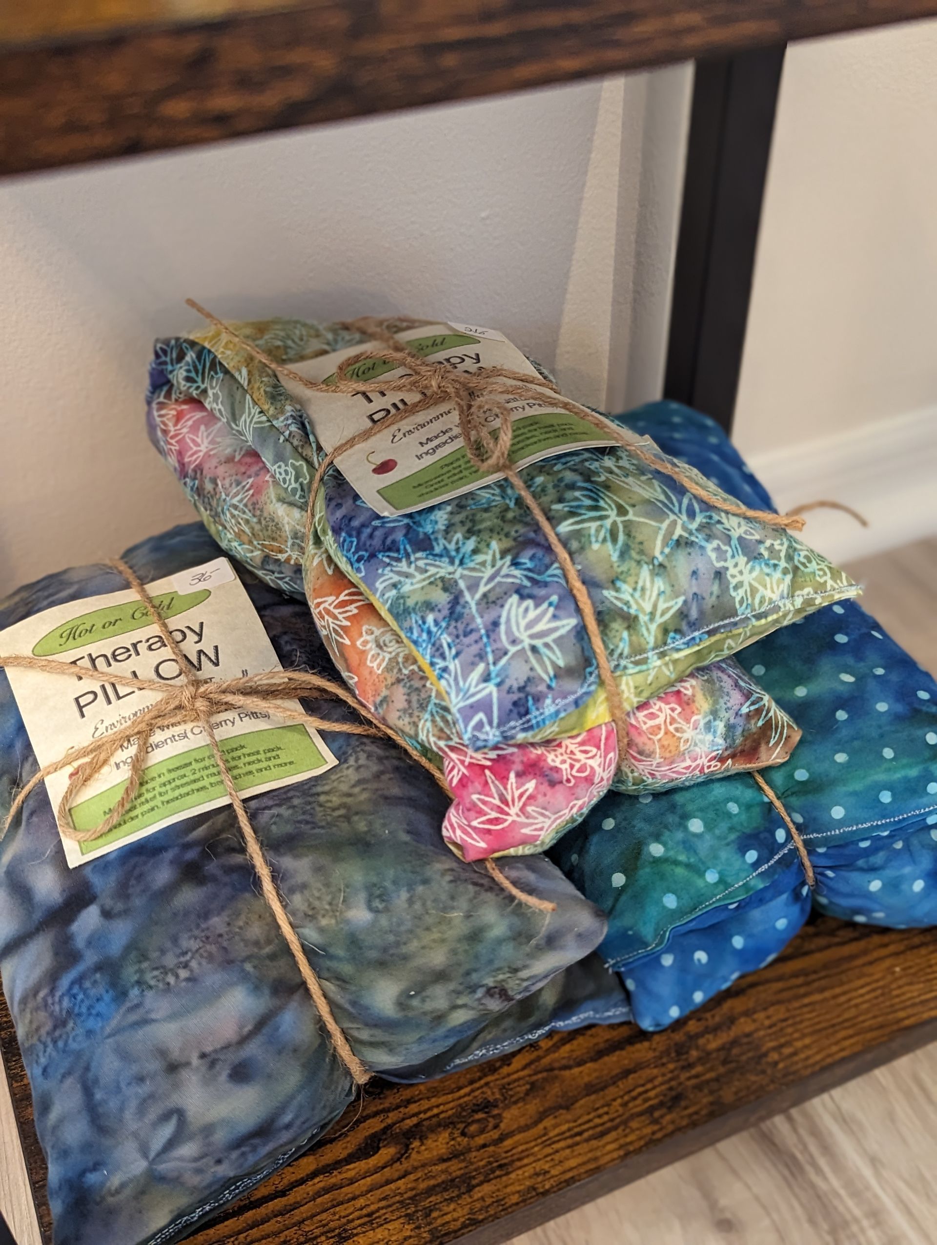 A stack of colorful pillows sitting on top of a wooden shelf.