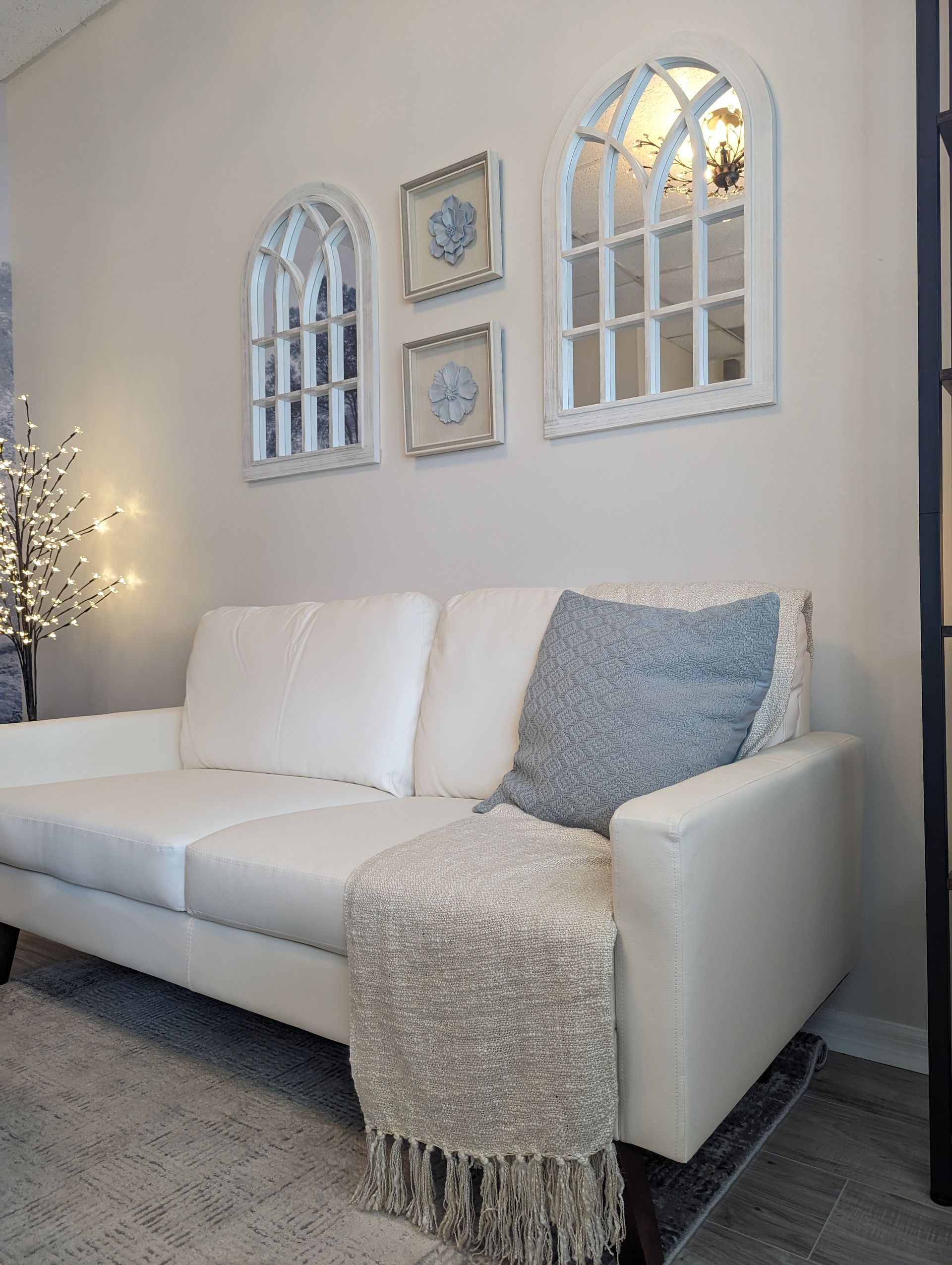 A white couch is sitting in a living room with mirrors on the wall.