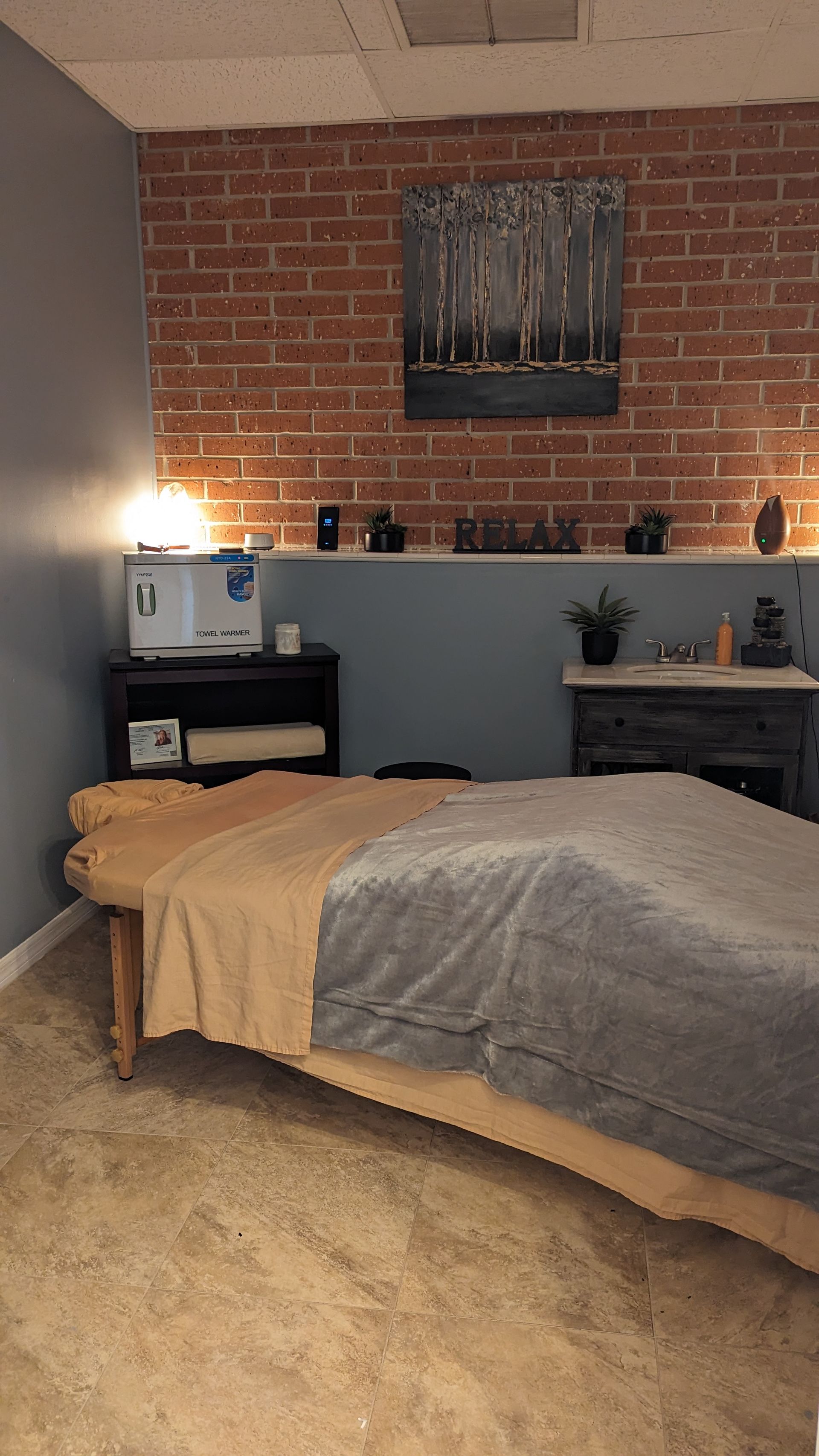 A massage table is sitting in a room with a brick wall.