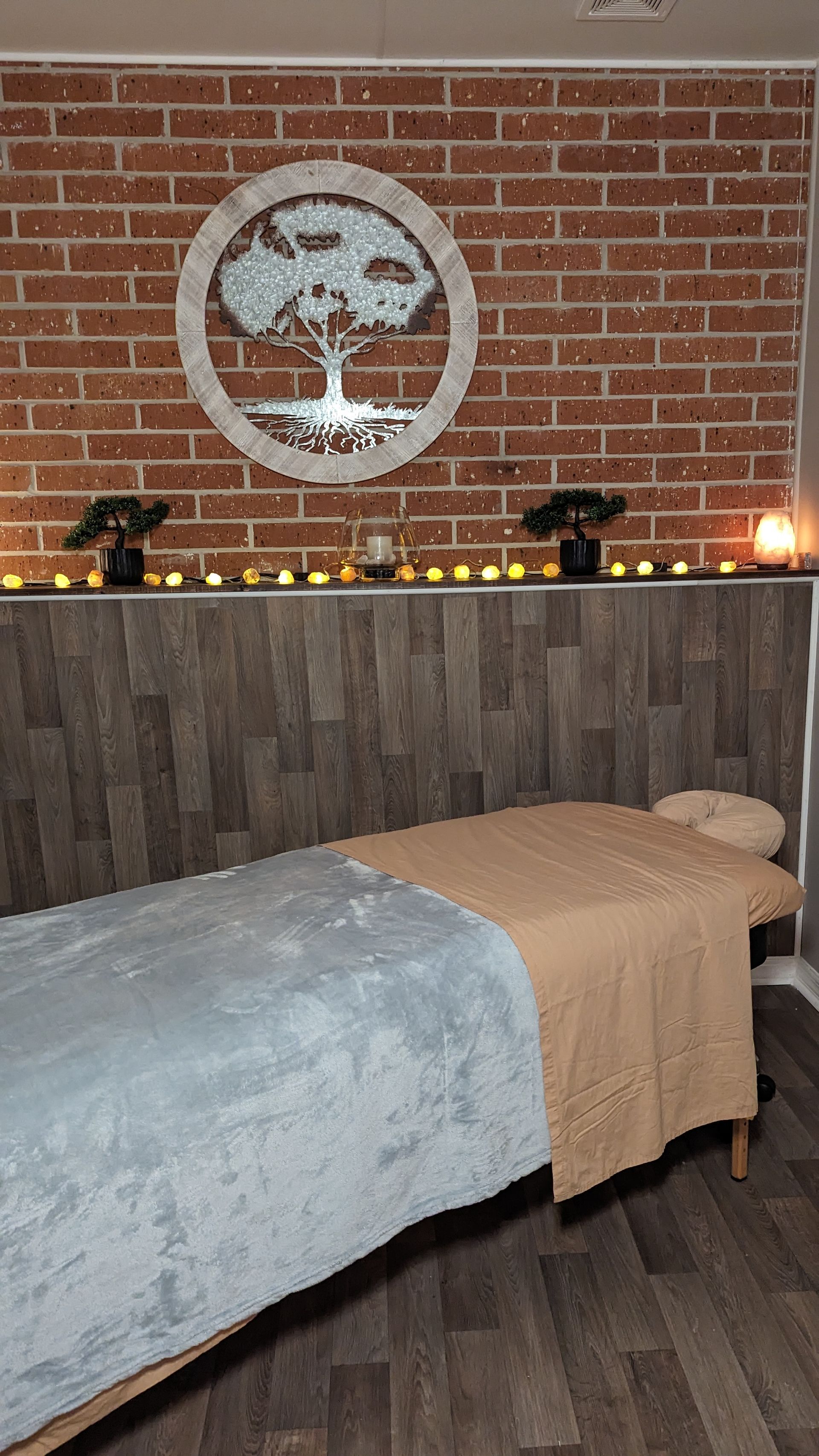 A massage table in a room with a brick wall and candles.