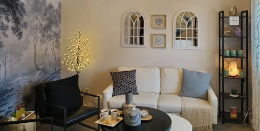 The front lobby of New Eden Spa with a couch , chair , table and mirrors.