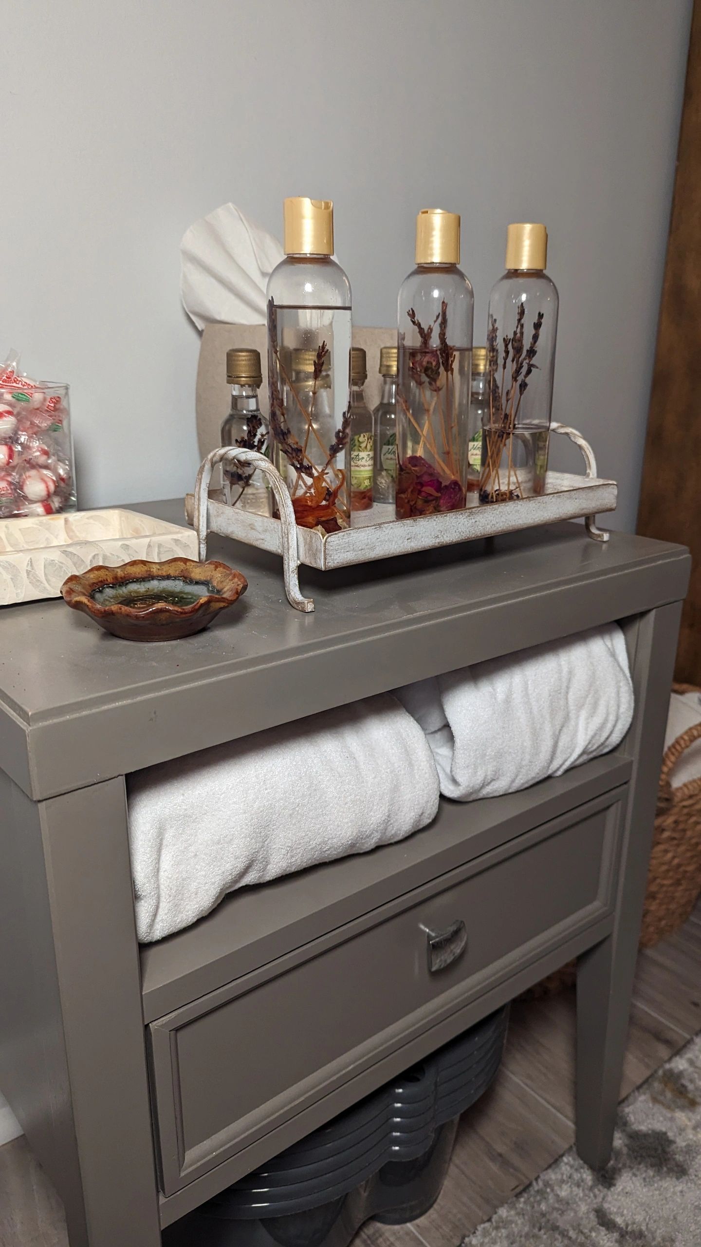 A nightstand with a tray of bottles and towels on it.