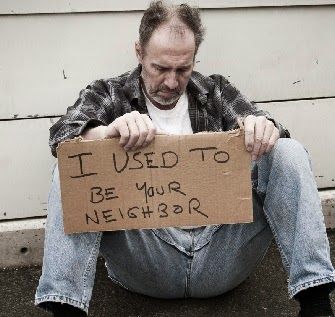 A man is sitting on the ground holding a sign that says i used to be your neighbor