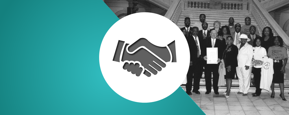 A group of people shaking hands in front of a building.