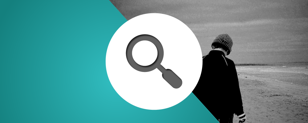 A person is standing on a beach with a magnifying glass.