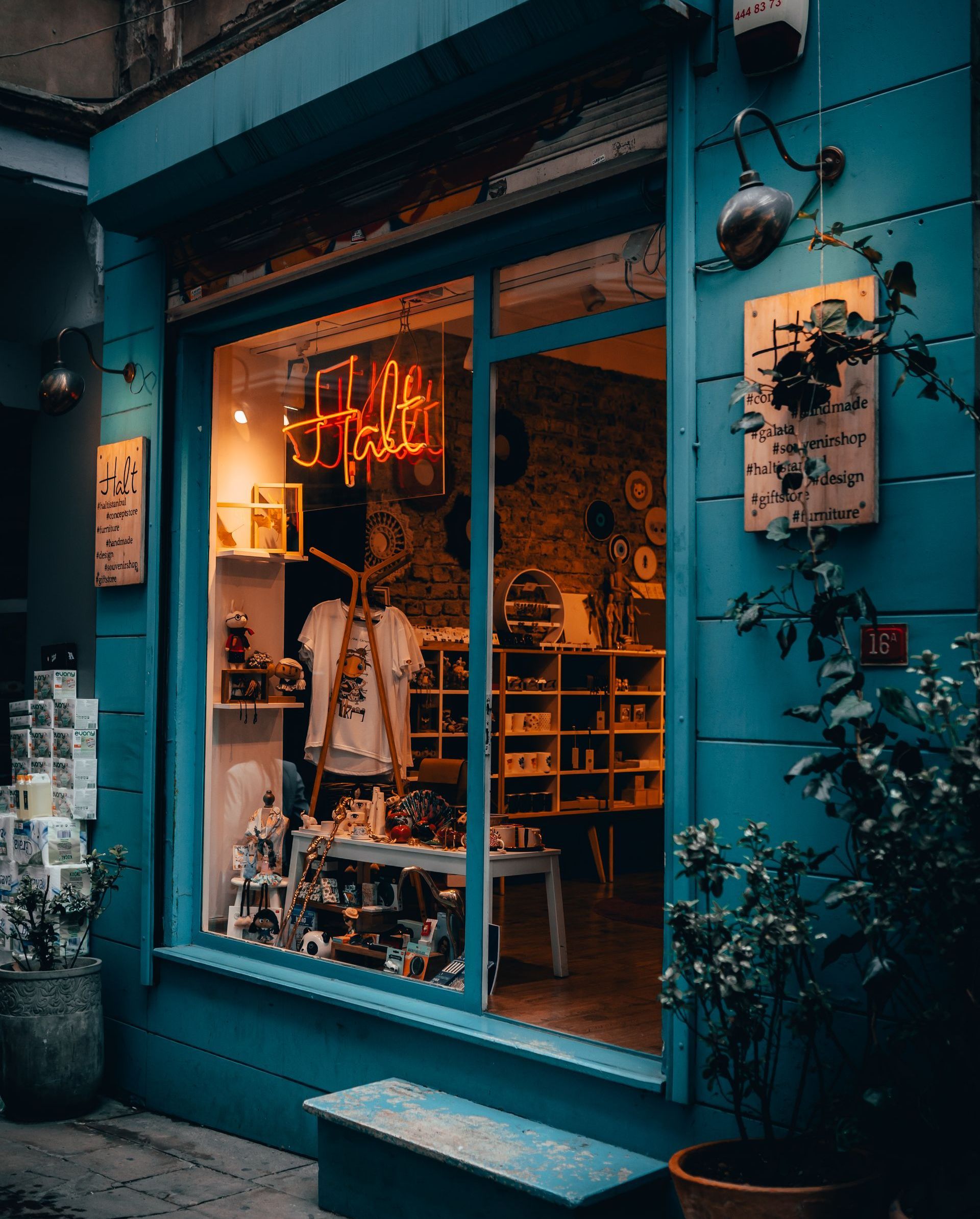 Blue shop exterior with a large window displaying merchandise; neon sign inside.
