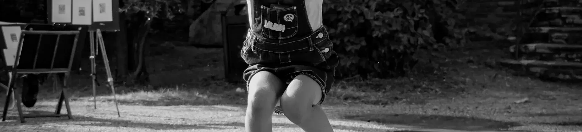 A person is dancing outside with an easel in the background, near some stairs and bushes.