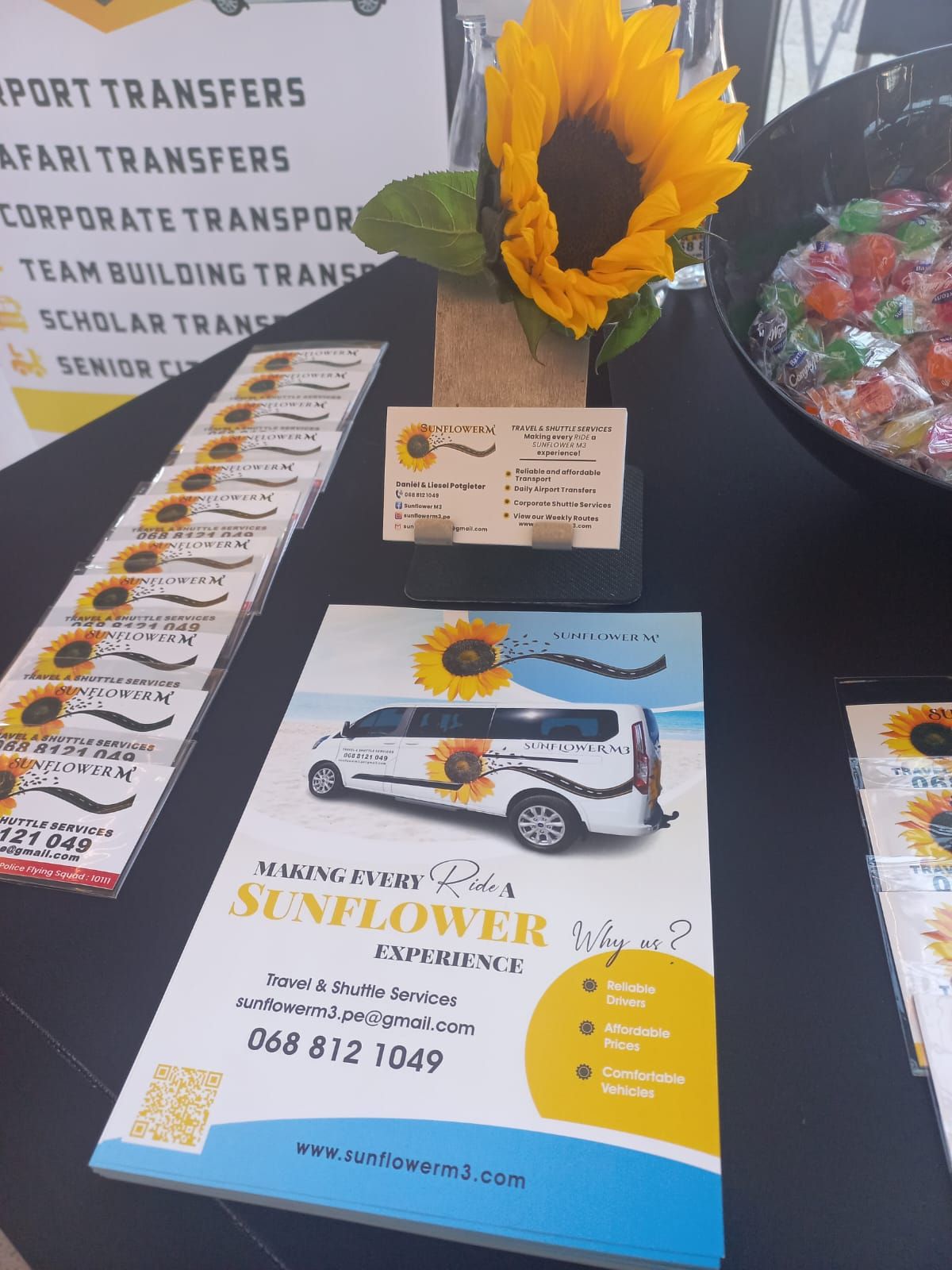 A display with brochures, business cards, and a sunflower decoration. The brochures advertise 