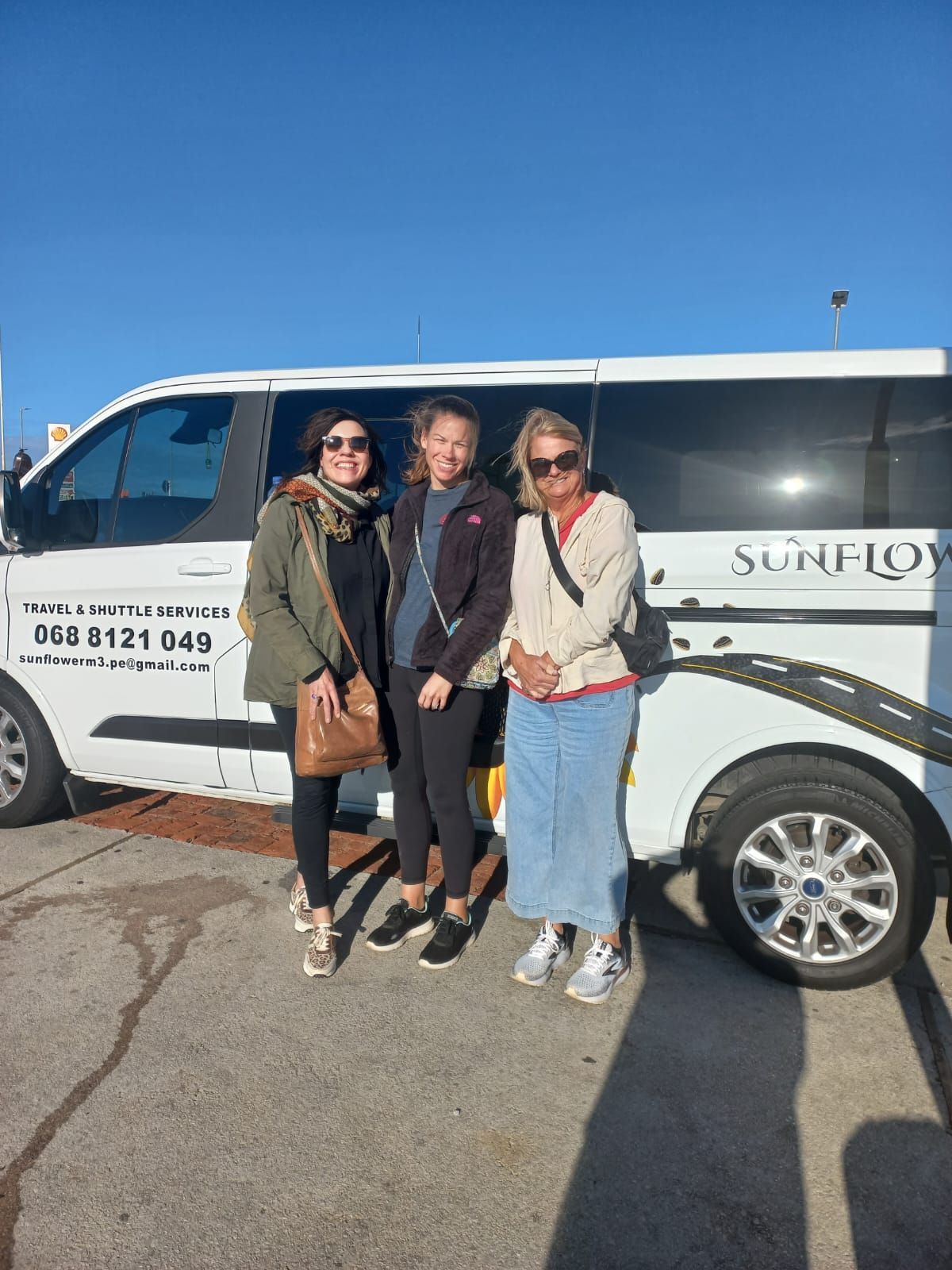 Three people stand next to a white van with 