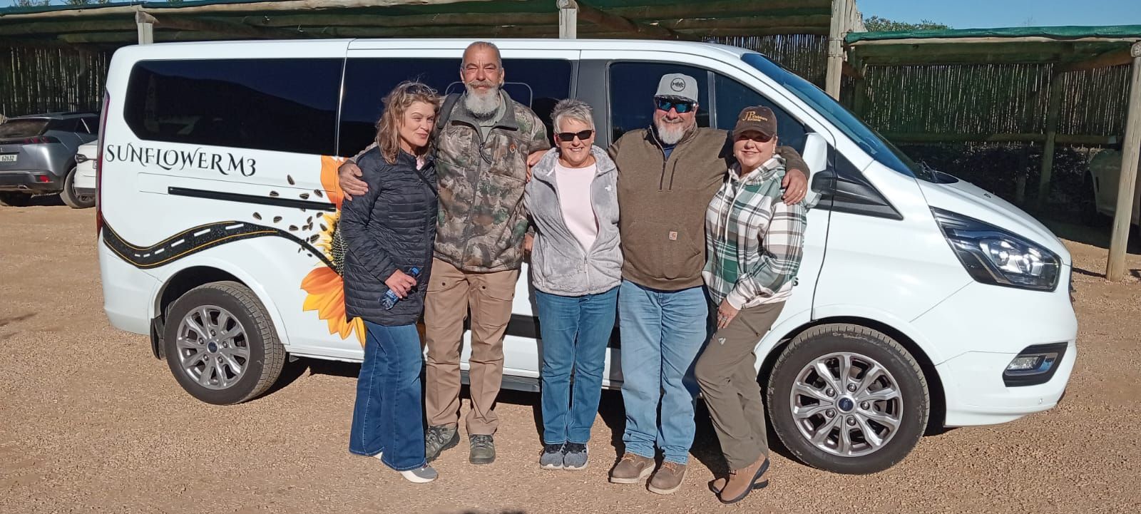 Five people stand next to a white van with 