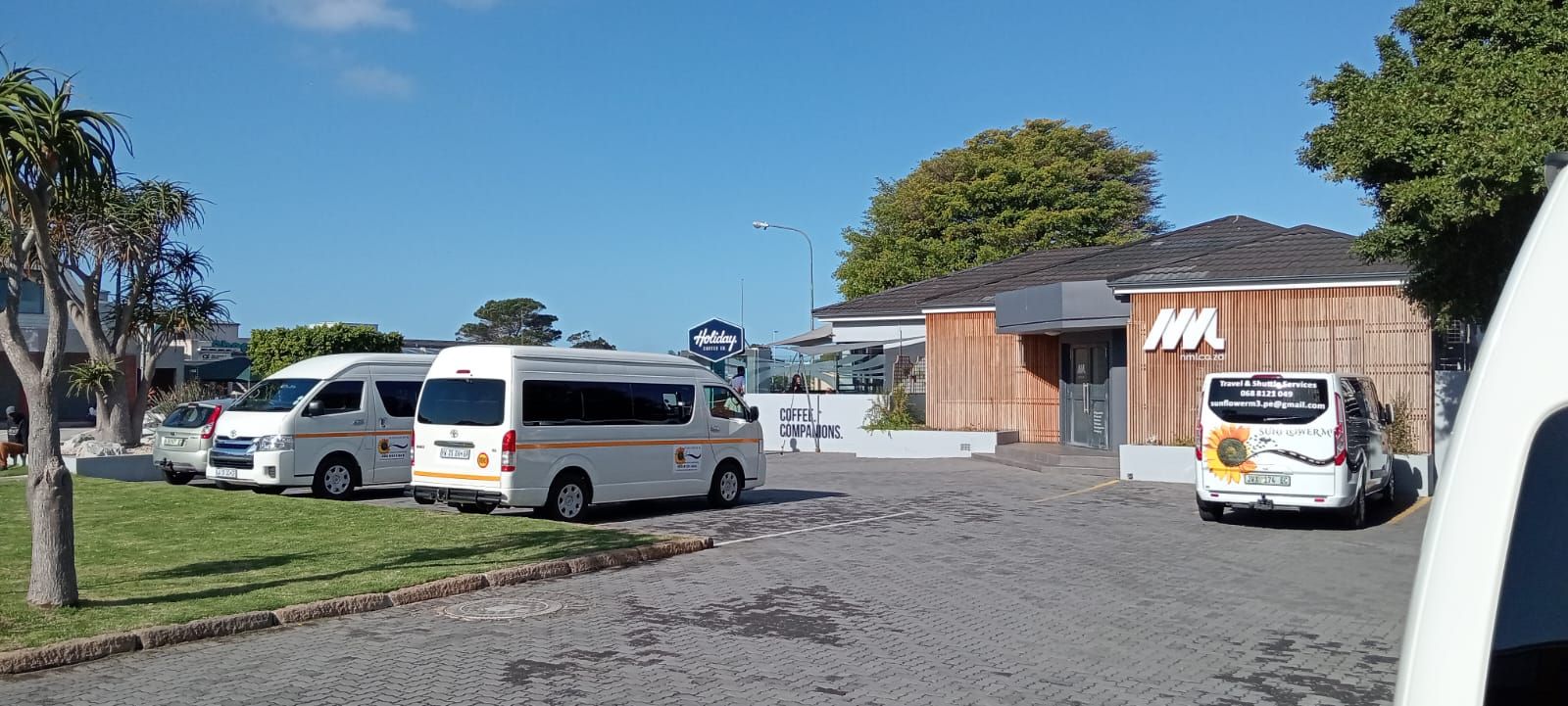 Several white vans parked near a building with a large 