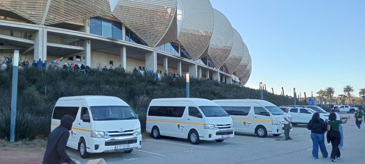 White vans parked near a large, modern building. People walk nearby.