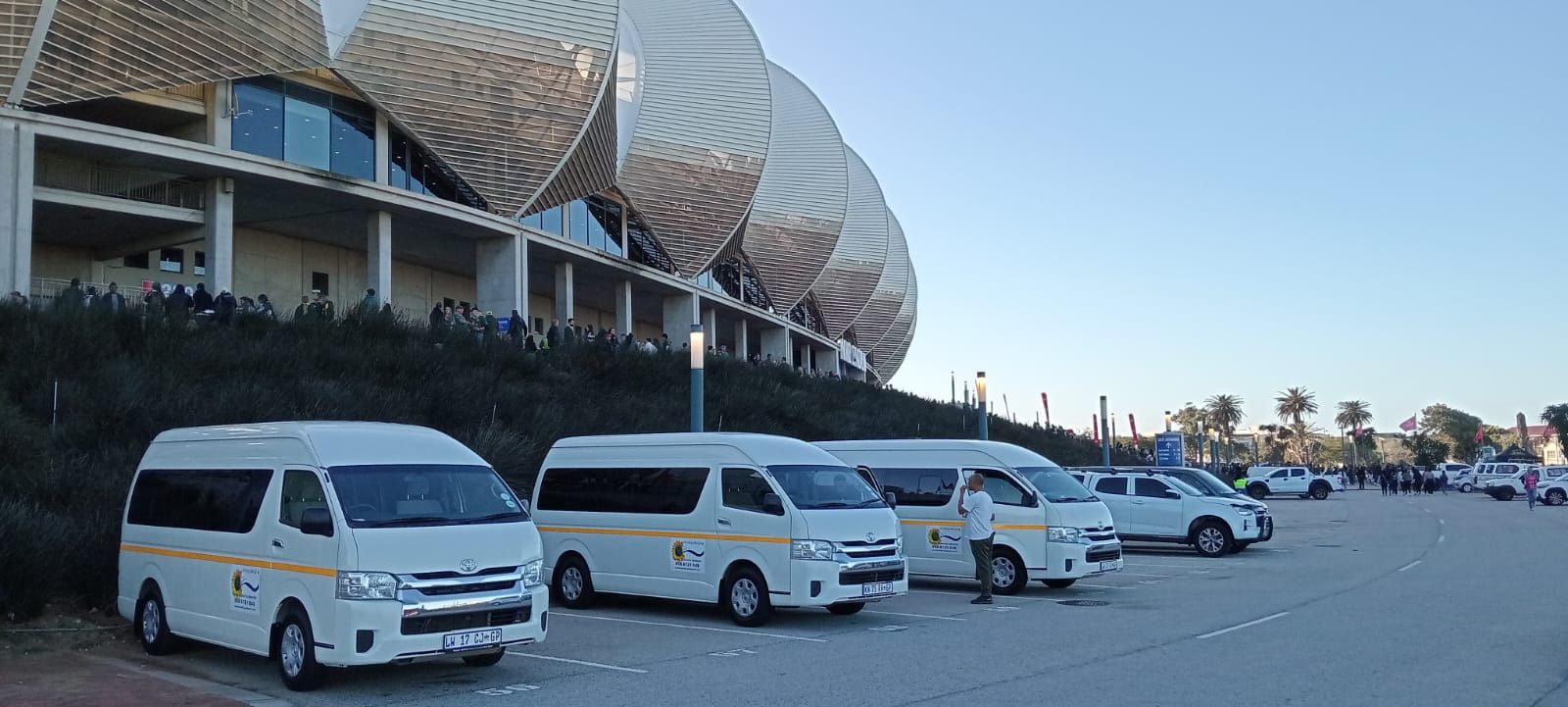 White vans parked in front of a modern building with a distinctive architectural design.