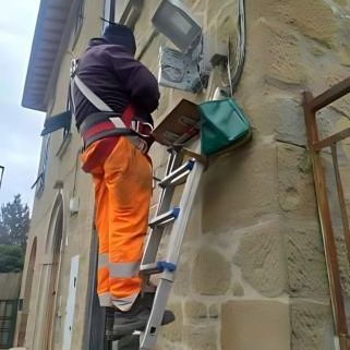 Un uomo con un gilet blu sta salendo su un palo