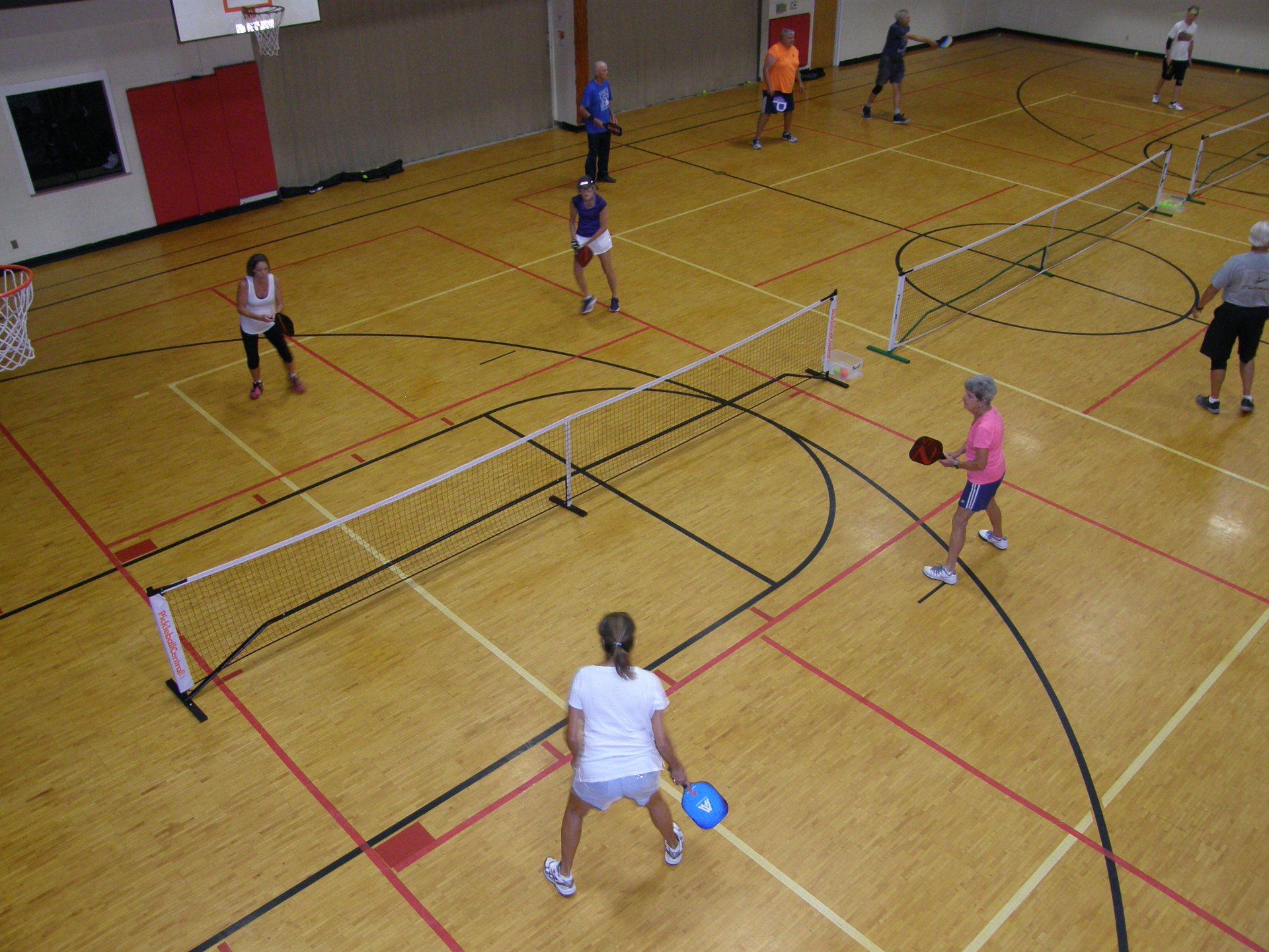 A group of people are playing a game of pickleball in a gym