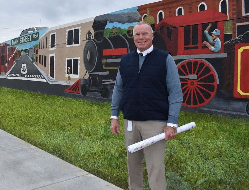 A man is standing in front of a train mural on a sidewalk