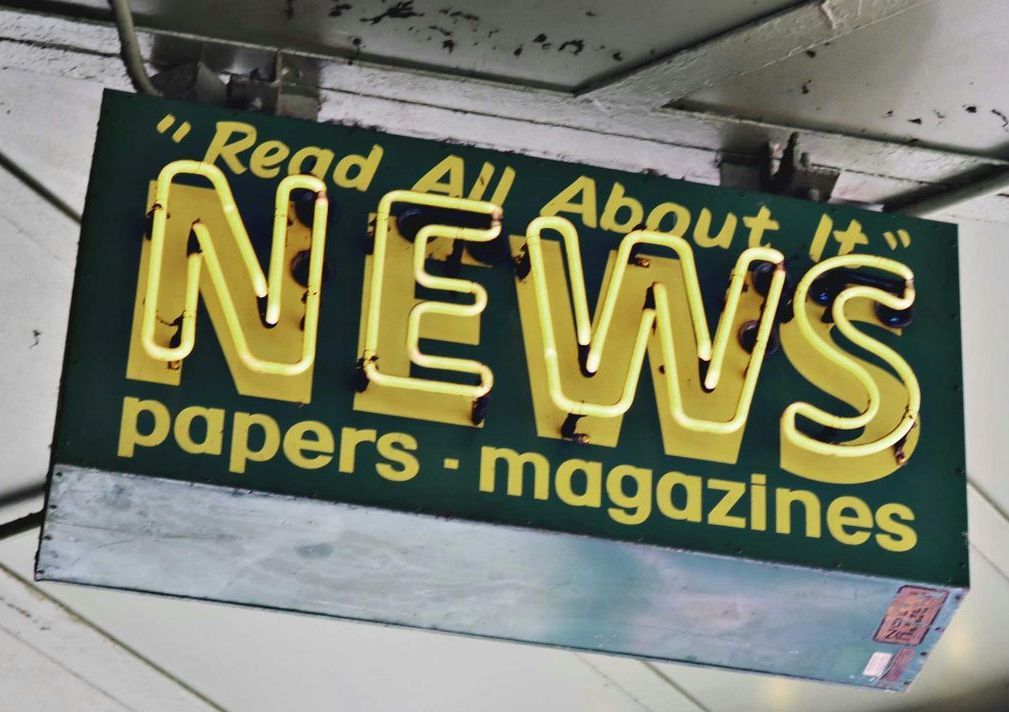 A sign that says read all about news papers magazines