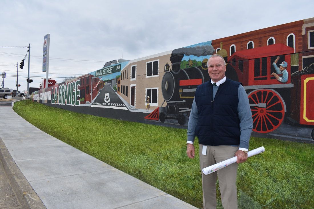 A man is standing in front of a mural of a train.