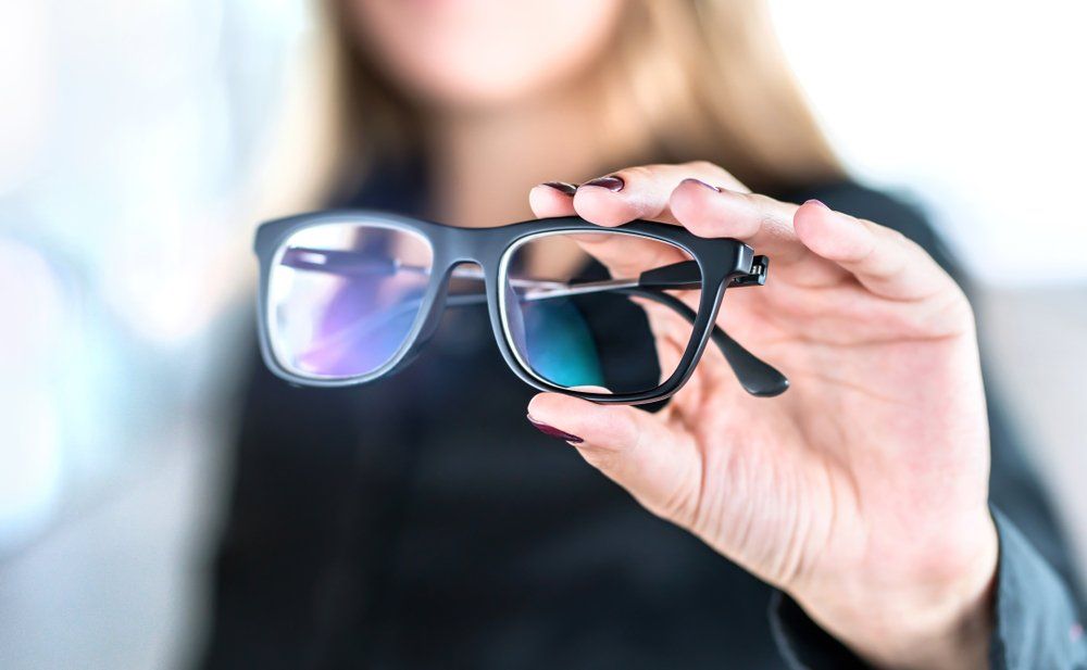 Optometrist Holding Glasses with New Lenses—  Russell Cooper Optometrist In Rockhampton QLD