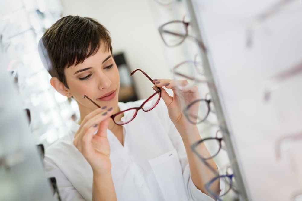 Woman in a White Coat Holding Red Eyeglasses — Russell Cooper Optometrist In Rockhampton QLD