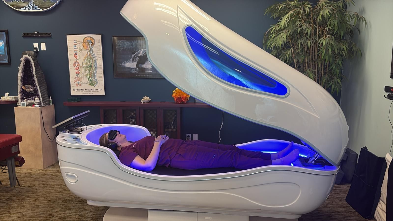 Woman inside a white spa bed with the lid open, blue lights, indoors.