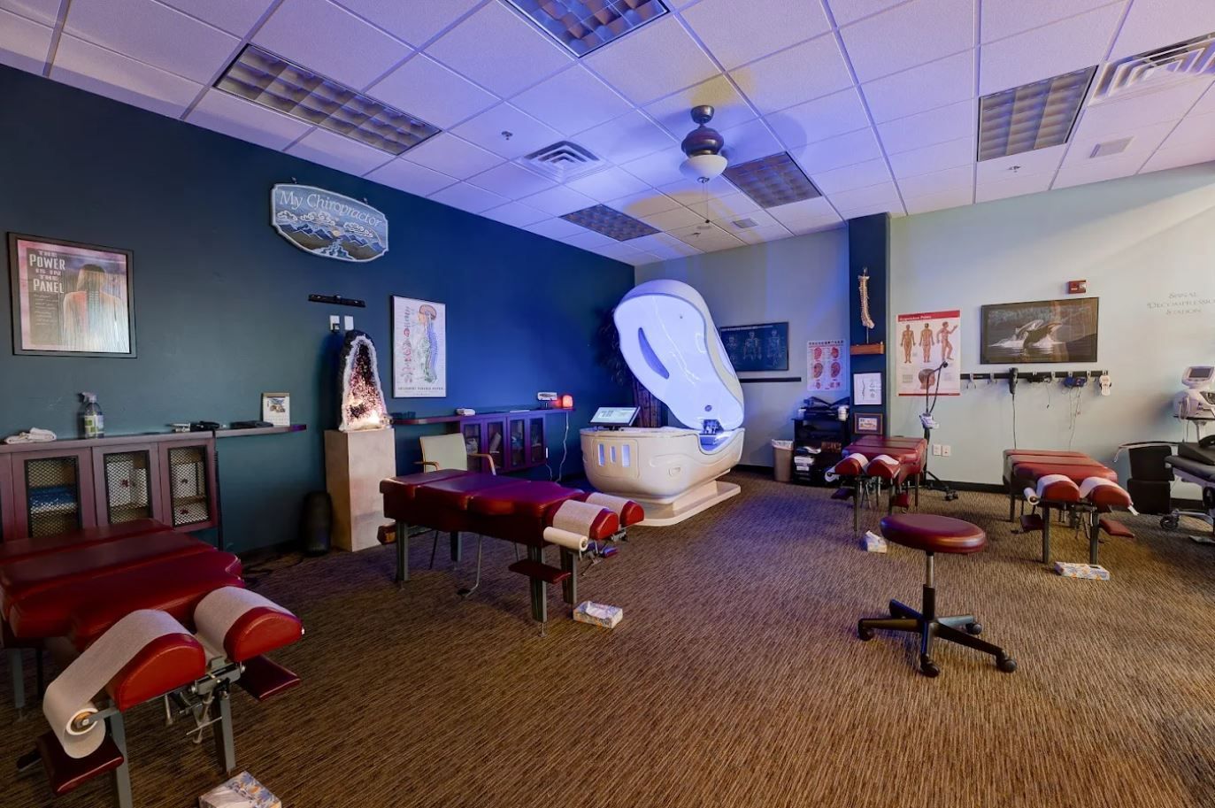 Chiropractor's office, with red tables and a large white cocoon-like machine in the center.