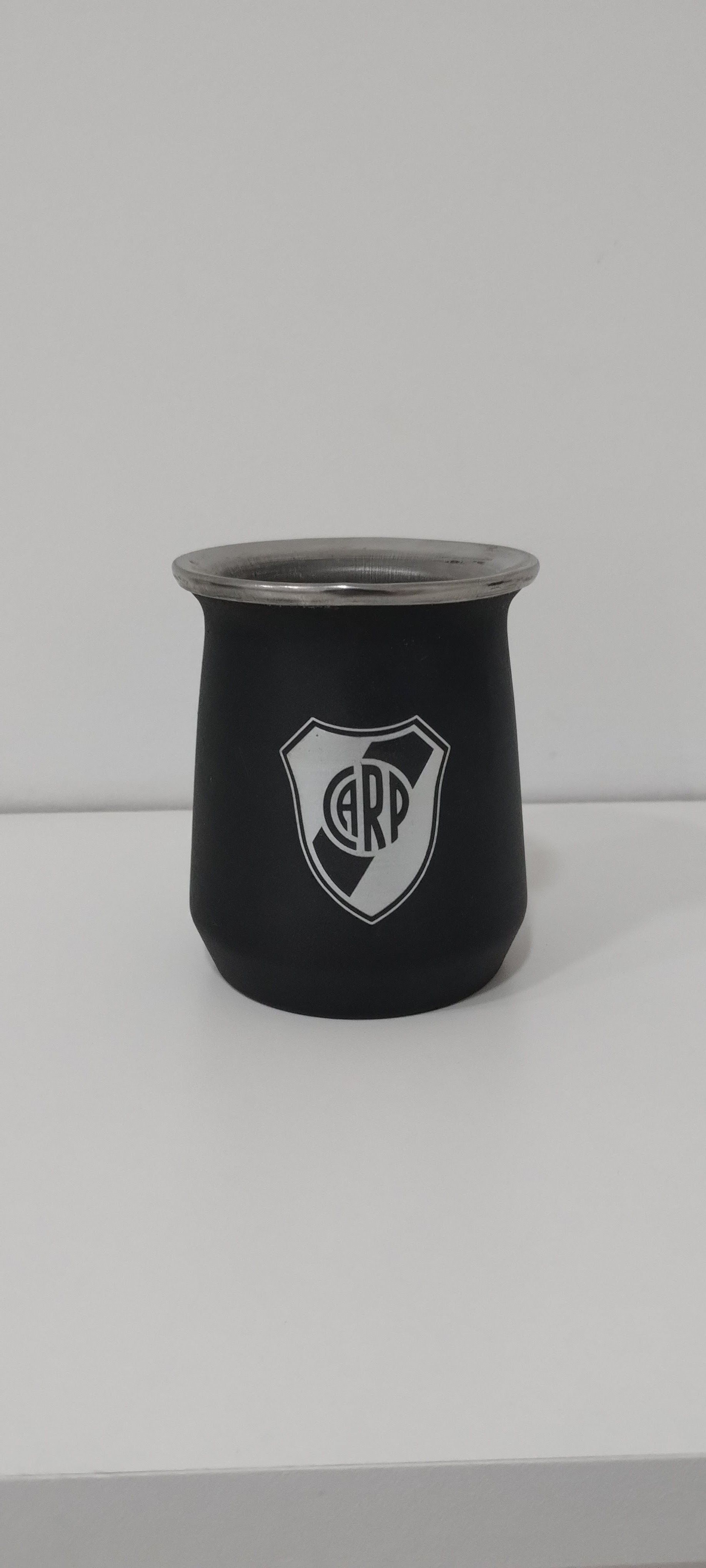 Matera de color negro con el logo del club River Plate sobre superficie blanca.