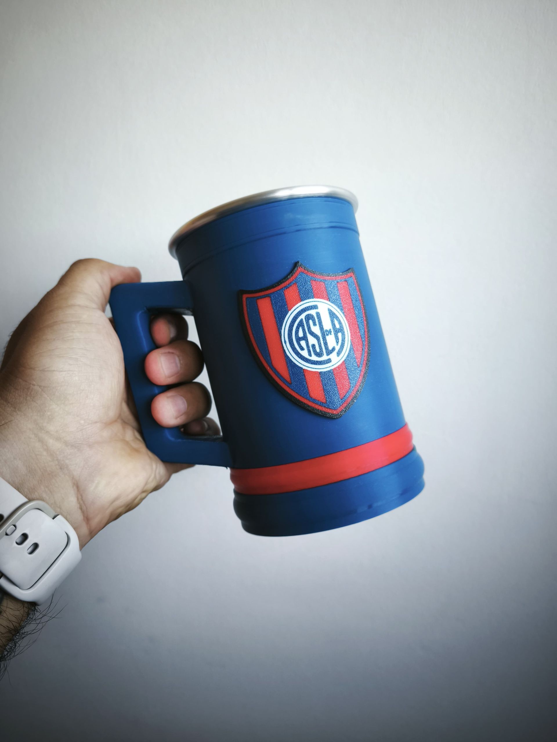 Mano sosteniendo una taza azul con un diseño de cuervo y el texto 