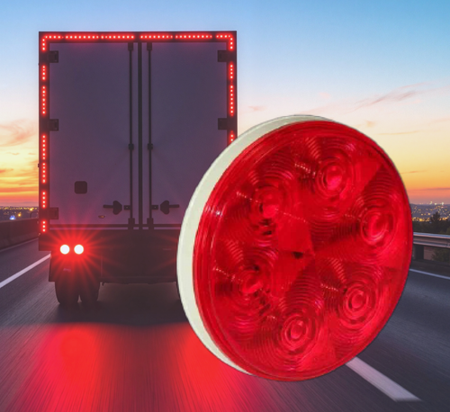 Red truck tail light with a semi-truck driving on a road at dusk.