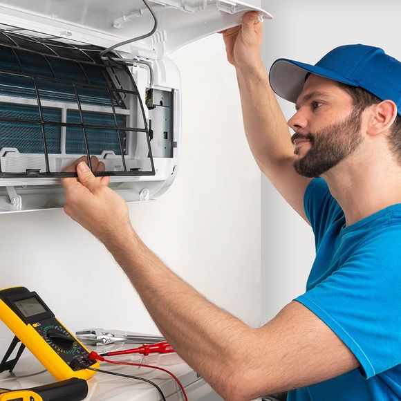 A Man Fixing Air Conditioner — East Bethel, MN — Heating And Cooling Solutions Inc