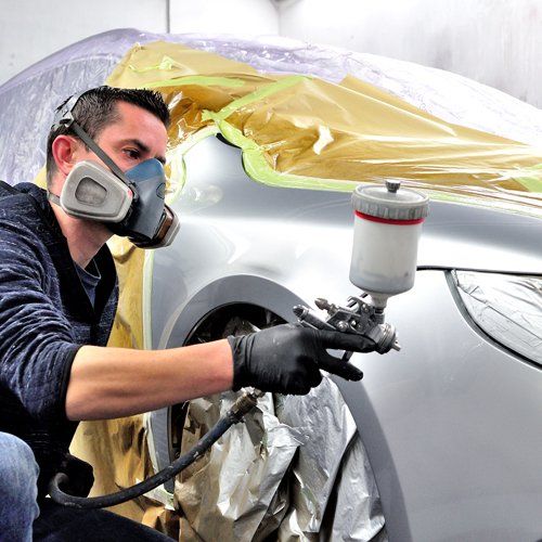 Auto body expert paints a car body parts — Port Allen, LA — Delaune’s Auto Body