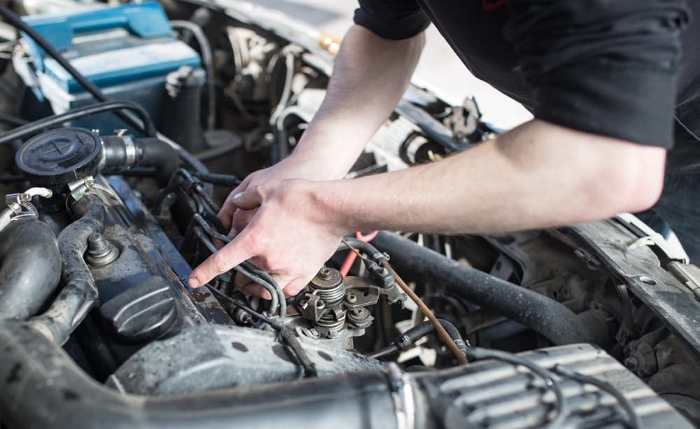 A Man is Working on the Engine of a Car — Mt Isa Four Wheel Drive Services in Mount Isa City, QLD