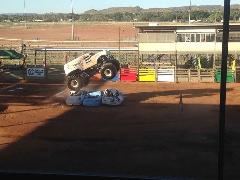 White Monster Truck Jumping Over Crushed Cars at a Dirt Track Event — Mt Isa Four Wheel Drive Services in Mount Isa City, QLD