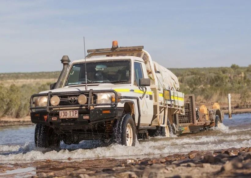 A White 4x4 Truck Fording a Shallow River — Mt Isa Four Wheel Drive Services in Mount Isa City, QLD