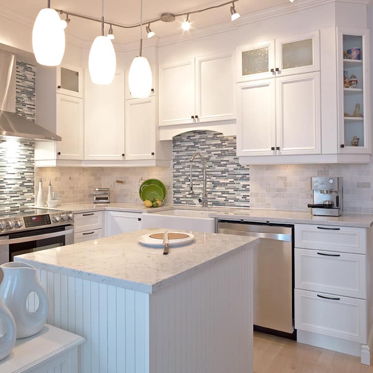 Une cuisine avec des armoires blanches et des appareils électroménagers en acier inoxydable