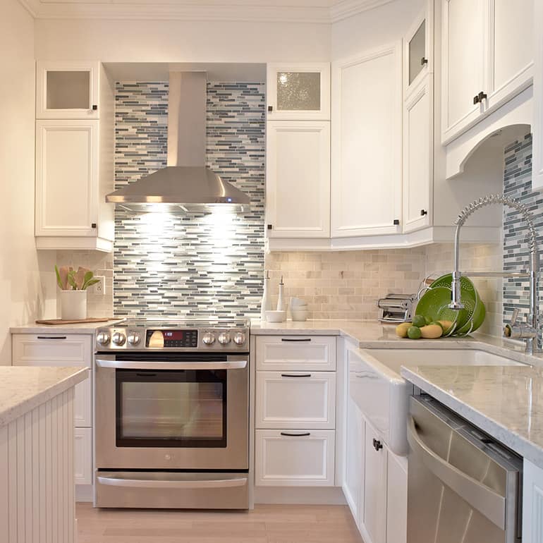 Une cuisine avec des appareils électroménagers en acier inoxydable et des armoires blanches