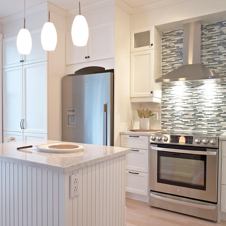 Une cuisine avec des appareils électroménagers en acier inoxydable et des armoires blanches