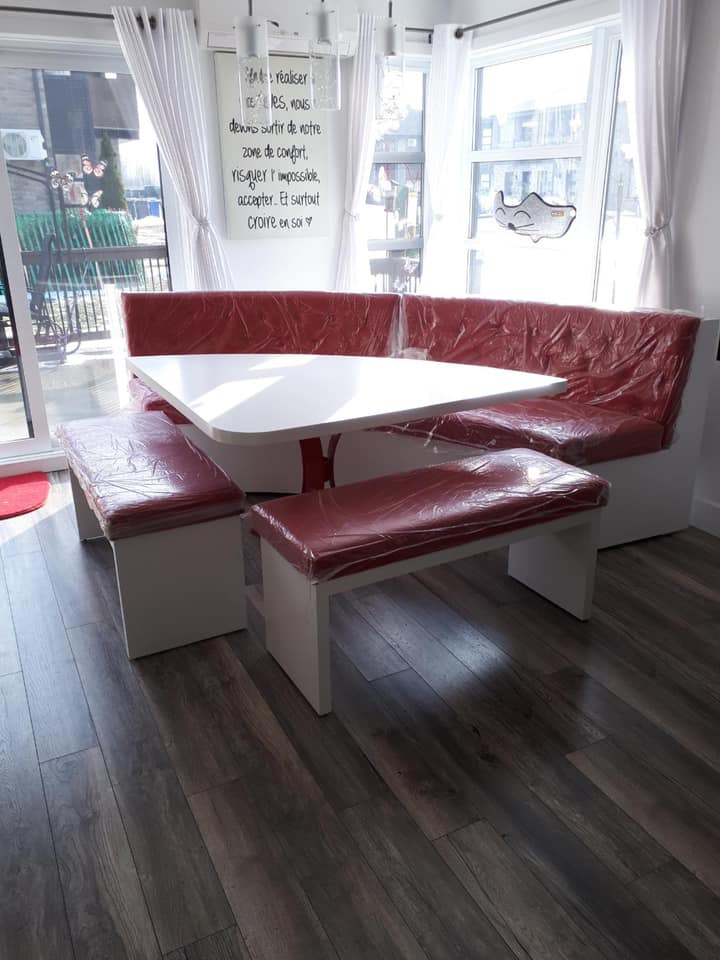 Une cuisine avec une table et des bancs devant une fenêtre.