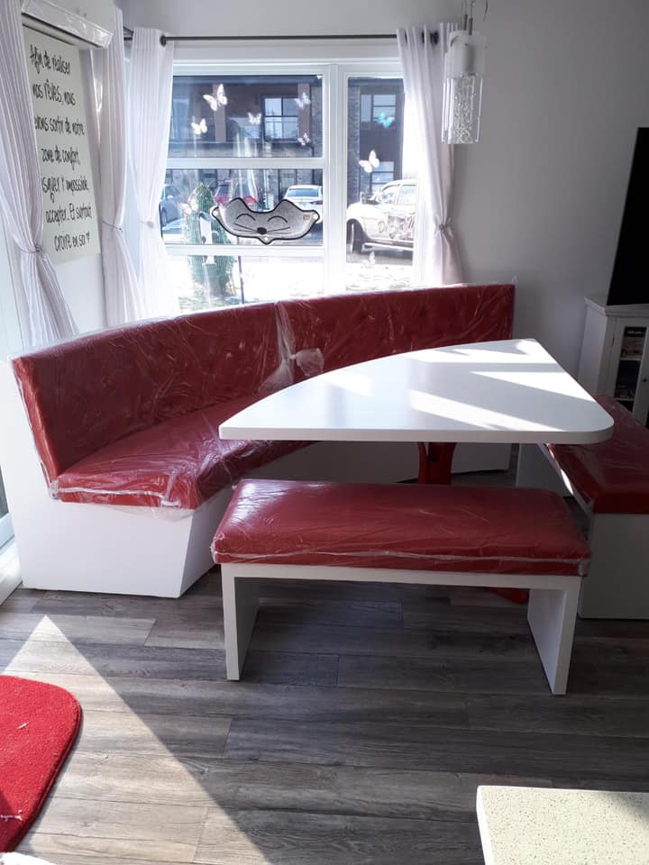 Un salon avec une table et des bancs devant une fenêtre.