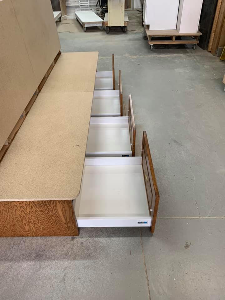 Une rangée de tiroirs posés sur un banc en bois dans un entrepôt.