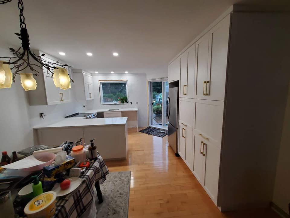 Une cuisine avec des armoires blanches et une table avec des assiettes dessus.