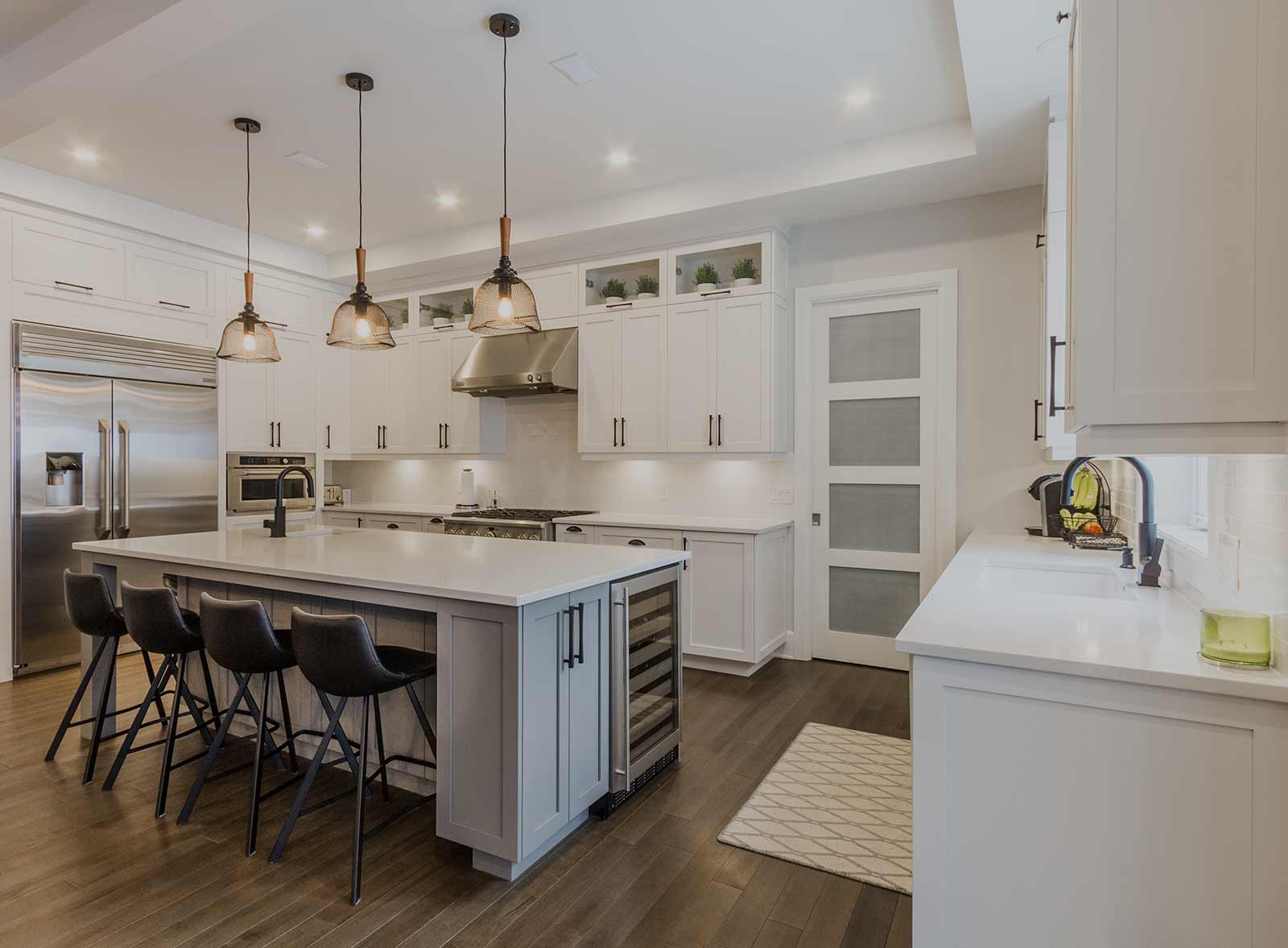 Une cuisine avec armoires blanches et électroménagers en acier inoxydable et un grand îlot.